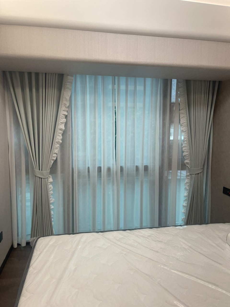 Graue Vorhänge mit Volant vor einem Bett